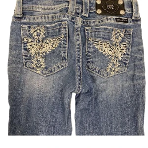 Miss me jeans med broderade fickor - Snygga blå bootcut miss me jeans med unika broderade detaljer på bakfickorna. Köpta här på plick. Defekter syns på bild tre(slitna längst ner i benen)