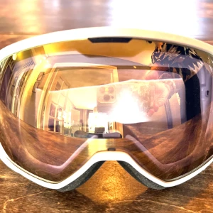 Vita skidglasögon från Scott - Snygga vita skidglasögon från Scott med spegelglas i bronze/ chrome av modellen Faze. De har en justerbar rem med logotyp och mjuk dubbel vaddering för komfort och bästa passform. Perfekta för vintersport och skyddar mot starkt solljus i backen.