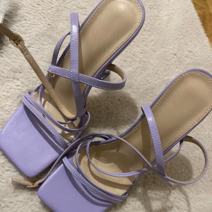 Lila sandaler med transparent klack - Snygga lila sandaler med flera remmar och en unik transparent klack. De har en fyrkantig tå och justerbara spännen för perfekt passform. Perfekta för att ge en färgklick till din outfit. Hälhöjd 10.5cm. Kan gå ner i pris!