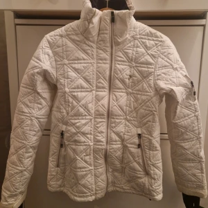 Vit jacka från Peak Performance - Säljer en snygg vit jacka från Peak Performance. Jackan har två dragkedjor framtill och två praktiska fickor med dragkedjor. Perfekt för kyligare dagar med sin stilrena design och bekväma passform.