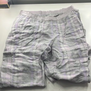 Grå och lila rutiga byxor från Kappahl - Säljer ett par bekväma grå och lila rutiga pyjamas byxor från Kappahl. De har en elastisk midja med texten 'UNIQUE' och är perfekta för en avslappnad stil. Materialet känns mjukt och skönt mot huden.