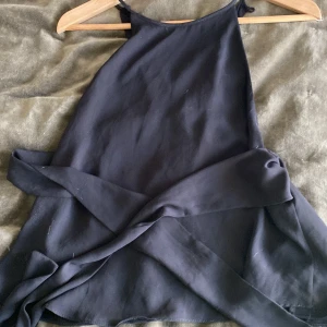 Topp från Zara - Snygg svart topp från Zara med knytband i midjan. Perfekt för en stilren look. Toppen har en enkel design med smala axelband och en elegant passform.