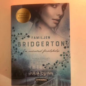 Familjen Bridgerton: En oväntad förälskelse - Boken 'Familjen Bridgerton: En oväntad förälskelse' av Julia Quinn är en del av den populära Bridgerton-serien. Omslaget har en elegant design med blå och grå toner samt en bild av en kvinna. Perfekt för dig som älskar romantiska berättelser i historisk miljö.