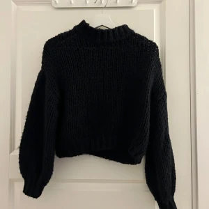Svart stickad tröja från NA-KD - Säljer en snygg svart stickad tröja från NA-KD. Tröjan har en hög krage och långa ärmar, perfekt för kyligare dagar. Den är både stilren och bekväm, ett måste i garderoben! 🖤
