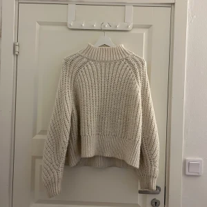 Cerimevit stickad tröja - Mysig stickad tröja med hög krage och långa ärmar. Perfekt för kyliga dagar med sin ribbade struktur och avslappnade passform. En klassisk och stilren design som passar till det mesta.