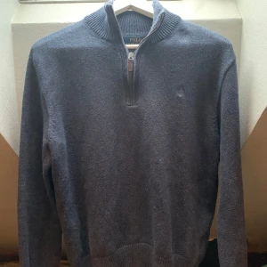 Mörkblå tröja från Ralph Lauren - Säljer en stilren mörkgrå tröja från Ralph Lauren med dragkedja vid halsen. Använd fåtal gånger, är lite liten i storlek så mer som s men passar m också 