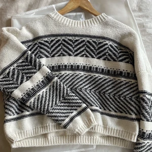 Otroligt fin vit och svart/blå stickad tröja  - Säljer denna otroligt fina vit och svartblåa stickade tröjan från Lindex. Den har långa ärmar och ribbstickade kanter vid hals, ärmslut och nederkant. Passar S som XS