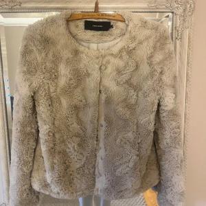 Beige pälsjacka från Vero Moda - Säljer en supermjuk och fluffig beige pälsjacka från Vero Moda. Jackan har långa ärmar och stängs med knappar framtill. Perfekt för att hålla sig varm och stilren under kyliga dagar. 🧥✨