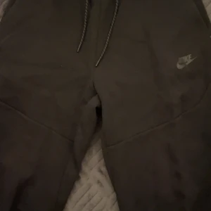 Svarta mjukisbyxor från Nike - Säljer ett par svarta mjukisbyxor från Nike med dragsko i midjan. Byxorna har en diskret Nike-logga på sidan och är perfekta för en avslappnad stil. Passar S också. Priset kan sänkas
