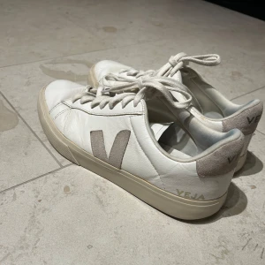Vita skor från Veja - Säljer ett par stilrena vita sneakers från Veja med grå/beige detaljer. Skorna har en klassisk design med märkets logga på sidan och hälen. De passar mycket bra på grabbar men även tjejer. Nypris: 1700 kr. Det lilla hålet i sulan LÄCKER EJ‼️Och borde gå att fixa med lite lim. Hålet finns på bild. Pris kan diskuteras!