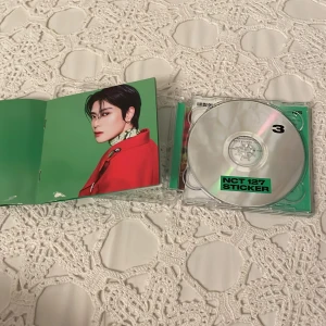 NCT 127 - Sticker (The 3rd Album) - Säljer NCT 127:s tredje album 'Sticker'. CD:n kommer i ett grönt fodral med en booklet som har bilder på medlemmarna. Perfekt för fans av K-pop och NCT 127! Skivan är i bra skick och innehåller flera populära låtar.
