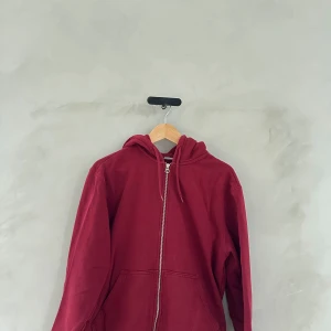 Vinröd hoodie med dragkedja - Säljer en mysig vinröd hoodie med dragkedja framtill. Perfekt för kyliga dagar och passar till både vardag och chill. Den har en luva med snören och långa ärmar. Superbekväm och stilren!