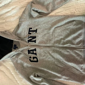 Grå hoodie från GANT - Säljer en snygg grå hoodie från GANT i storlek L som även passar S/M som jag har i bilden. 