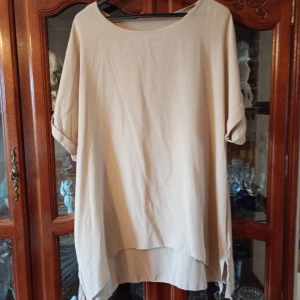 Set blus/byxa stl L/Xl - Helt i nyskick set med byxa med resår i midjan svängda ben öppning ner till samt blus kort fram och längre bak stl L/XL .100 polyester. Beige.