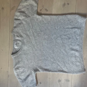 Grå kashmirtröja från Soft Goat - Säljer en supermjuk och stilren grå kashmirtröja från Soft Goat. Perfekt för kyliga dagar med sin klassiska design och korta ärmar. Tröjan är tillverkad i 100% kashmir. Orginalpris: 1995