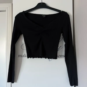 Svart ribbad topp från Monki - Snygg svart ribbad topp från Monki i storlek XS. Toppen har en v-ringning och långa ärmar, med en fin rynkdetalj framtill. 