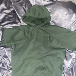 Grön hoodie från BikBok - Säljer en grön hoodie från BikBok i storlek S. Den har en klassisk design med en stor ficka framtill och justerbar dragsko i huvan. Perfekt för en avslappnad stil.