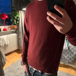 Vinröd tröja från Uniqlo - Säljer en stilren vinröd tröja från Uniqlo. Tröjan har en klassisk rund hals och långa ärmar, perfekt för kyligare dagar. Storlek M men skulle säga att den sitter som en XS då den krympt.