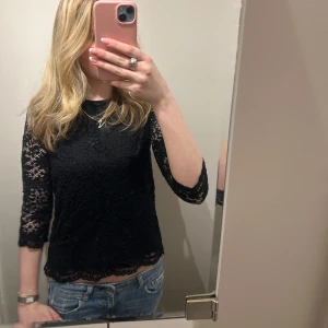 Svart spetsblus - Säljer en elegant svart spetsblus med trekvartsärm. Perfekt för en stilren look. Blusen har en fin spetsdesign som ger en feminin touch.