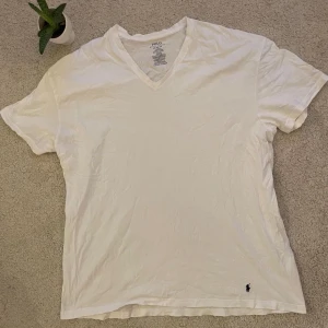 Vit t-shirt från Polo Ralph Lauren - Säljer en klassisk vit t-shirt från Polo Ralph Lauren i storlek 2XL. T-shirten är tillverkad i 100% bomull och har en stilren v-ringning. Perfekt för en avslappnad stil.