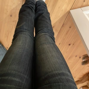 Mörk blåa  jeans med kronor på backfickan från Victoria Beckham - Snygga svarta jeans från Victoria Beckham med glitter kronor på bakfickan. Jeansen har en tight passform på mig är lite försmå men passar ändå. Dem är i nytt sick tre paljetter är borta från baksidan och knappen därframme är utbytt, eftersom den originals försvan för många år sedan.