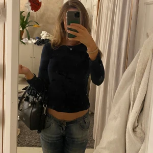 Svart långärmad topp med snörning - Säljer en stilren mörkblå långärmad topp med snygg snörning i ryggen. Perfekt för en trendig look. Passar bra till jeans eller kjol. Hör av dig vid intresse!