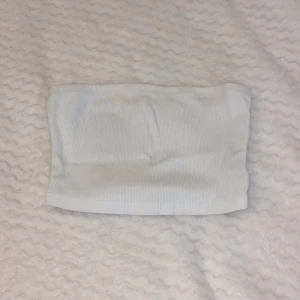 Vit ribbad tubtopp - Säljer en stilren vit ribbad tubtopp. Perfekt för sommardagar eller som ett basplagg i garderoben. Enkel och bekväm design som passar till många olika outfits.