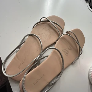 Silvriga sandaler från Divided - Snygga silvriga sandaler från Divided med tunna remmar. Perfekta för sommardagar och enkla att matcha med olika outfits.