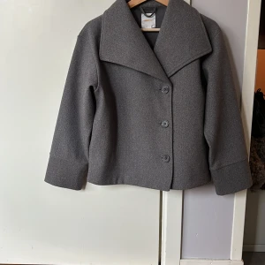 Grå kappa från Gina Tricot - Säljer en stilren grå kappa från Gina Tricot💕Jackan har en klassisk design med stora knappar framtill och en bred krage💕Jackan är en vår och höstjacka i mycket gott skick, sparsamt använd💕Nypris är 399 kr💕säljer den för 175  kr💕💕Hör av er vid intresse av kappan💕💕💕