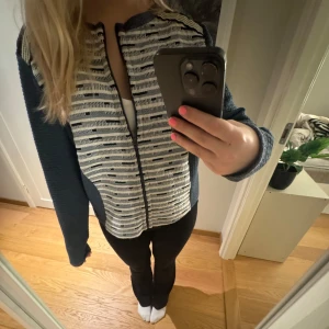 Mönstrad jacka med dragkedja - Säljer en snygg jacka med dragkedja och unikt mönster i blått och vitt. Jackan har långa ärmar och en bekväm passform. Perfekt för att ge din outfit en stilfull touch.