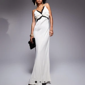 Vit långklänning med svarta detaljer - Säljer denna superfna klänning som är helt slutsåld på hemsidan. Klänningen är oanvänd med lappar kvar, nypris 789 kr