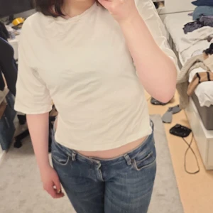 Vit kortärmad topp från Nelly - Säljer en söt vit topp från Nelly i storlek XXS. Toppen har korta ärmar och en knytning i ryggen som ger en fin detalj. Den är väldigt luftig och sval till sommaren!