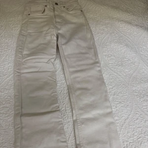 Beige jeansbyxor - Snygga beige jeansbyxor med klassisk femficksdesign och knappgylf. Perfekta för en stilren look. Passar bra till både vardag och mer uppklädda tillfällen.