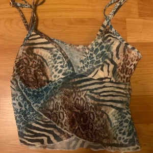 Mönstrad linnetopp från Shein - Snygg och trendig linnetopp från Shein med djurmönster i olika nyanser av turkos och brunt. Toppen har smala axelband och en omlott-design framtill. Storlek S.