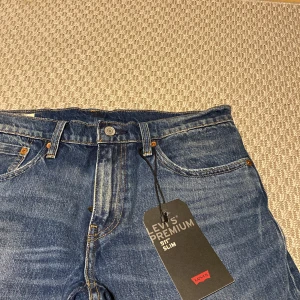 Blå Levis 511 Slim Jeans - Snygga blå Levis 511 Slim jeans med en klassisk femficksdesign. De har en lätt slitning på framsidan och en bekväm passform. Perfekta för en stilren look. Nya! 