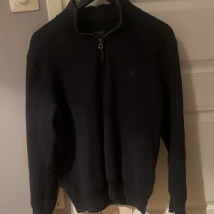 Mörkblå tröja från Polo Ralph Lauren/Mesh-Knit Cotton Quarter-Zip Jumper - Säljer en stilren mörkblå tröja från Polo Ralph Lauren. Tröjan har en dragkedja vid halsen och är långärmad. Rätt liten i Storlek. Inköpt för 2200 kronor på Åhléns i Stockholm. Kan gå ner lite i pris vid snabb affär. 