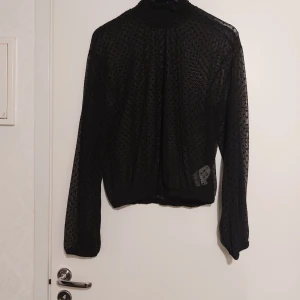 Svart transparent prickig blus - Säljer en svart transparent blus från H&M med prickigt mönster. Blusen har långa ärmar och en elastisk nederkant. Perfekt för att lägga till en stilfull touch till din outfit. 🖤