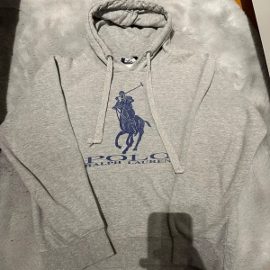 Grå hoodie från Ralph Lauren - Tja, Säljer en stilren grå hoodie från Ralph Lauren. Den har inga defekter utöver det som syns på ena snöret! Hör av er vid eventuella frågor eller funderingar!