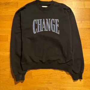 Svart sweatshirt med texten 'CHANGE' - Snygg svart sweatshirt med texten 'CHANGE' i blått och vitt på framsidan. Tröjan har långa ärmar och ribbade muddar vid ärmslut och nederkant. Perfekt för en avslappnad stil. Den kommer från märket VALIANT. Bra skick
