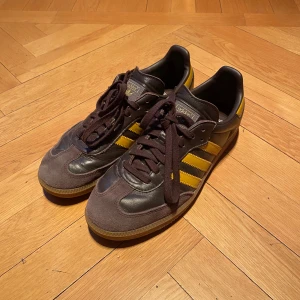 Adidas Samba Bruna/Gula Läder - Säljer för att de är för små. Nypris: 2200 kr. Snygga Adidas Samba sneakers i brunt skinn med gula detaljer. De är  använda de är sparsamt använda. Ikonisk design som aldrig går ur stil. Storlek 42 2/3 men passade min när jag hade 43. Hör av er om ni har frågor ellee diskutera pris