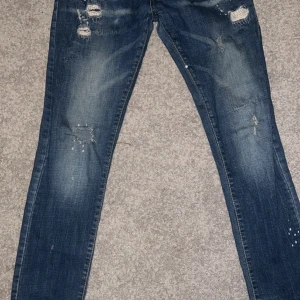 Blå jeans från Dsquared2 - Snygga blå jeans från Dsquared2 med slitna detaljer och en klassisk femficksdesign. Jeansen har en knappgylf och är tillverkade i ett robust denimtyg. Perfekta för en avslappnad stil.