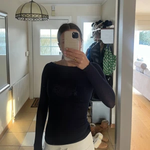 Mörkblå Intimissimi topp - Säljer en mörkblå långärmad Intimissimi topp i kashmir med en tight passform. Toppen är enkel och stilren, vilket gör den lätt att matcha med olika outfits. Den har två små hål men de är små- se på bilden. Kom privat för fler frågor!!