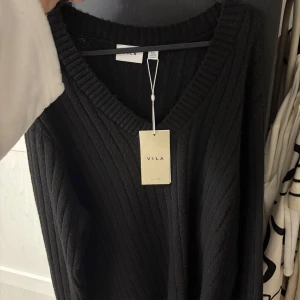 Svart ribbad tröja från VILA - Säljer en stilren svart ribbad tröja från VILA med v-ringad hals. Perfekt för en avslappnad och trendig look. Tröjan har långa ärmar och är gjord i ett mjukt material.