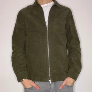 Overshirt - Snygg grön manchesterjacka från Riley.  med dragkedja framtill. Jackan har en klassisk krage och en bröstficka. Perfekt för en stilren look. Nypris på denna är 1200kr! Den är i storlek s och modellen är 180cm lång. Vid övriga funderingar eller frågor är det bara höra av sig!🙌