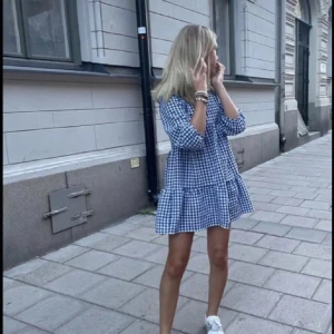 Blårutig klänning - ❣️lånad första bild❣️Charmig blårutig klänning med volangdetaljer och trekvartsärmar. Perfekt för en avslappnad och stilren look❣️❣️❣️ett litet hål som knappt syns