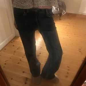 Mörkblå jeans med bootcut - Snygga mörkblå jeans med bootcut-stil och låg midja. Perfekta för en avslappnad look. Klassisk design med dragkedja och knappar framtill.