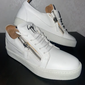 Vita Giuseppe Zanotti - Snygga vita sneakers från Giuseppe Zanotti med dragkedja och snörning. Skorna har en stilren design med en tjock sula och är perfekta för en trendig look. Helt nya , storlek 41 , skriv för mer info! 