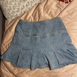 Blå jeanskjol - Säljer en snygg blå jeanskjol med volangdetaljer. Kjolen är från H&M devided. Storlek xxs 