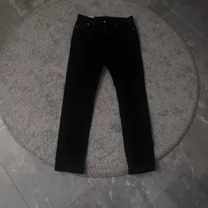 Svarta slim fit byxor från H&M - Snygga svarta slim fit byxor från H&M. Perfekta för en stilren look. Byxorna har en klassisk design med dragkedja och knapp framtill.