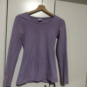 Lila långärmad topp från Gina Tricot - Säljer en stilren lila långärmad topp från Gina Tricot i storlek XS. Perfekt för lager-på-lager eller som den är. Enkel och bekväm design som passar till många tillfällen.